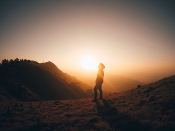 Silhouette woman standing on mountain against sky during sunset