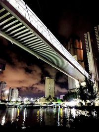 Bridge over illuminated buildings against sky at night