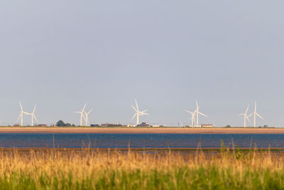 Wind turbines on field against sky