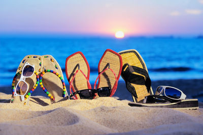 Close-up of slippers on sand at beach during sunset