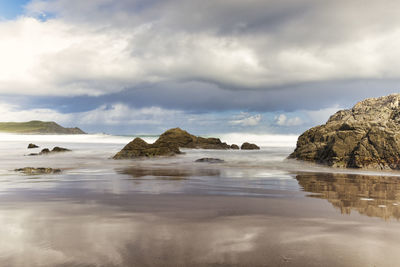 Scenic view of rocks on sea against sky