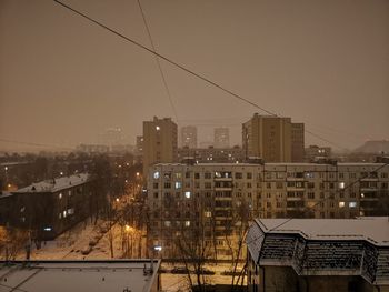 Illuminated buildings in city against sky at dusk