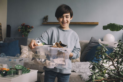 Portrait of happy boy carrying paper in container at home