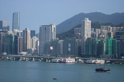 Modern buildings by sea against sky in city