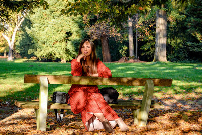 Portrait of woman sitting on bench in park.