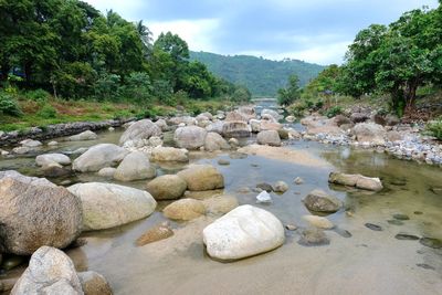 Rocks by river against sky