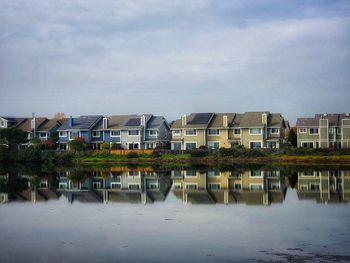 Buildings by lake against sky