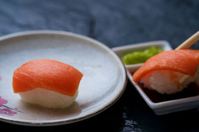 Close-up of sushi in plate by soya sauce on slate