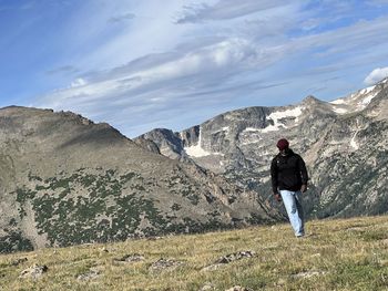 Rear view of man standing on mountain against sky