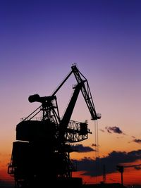 Low angle view of silhouette crane against clear blue sky at dusk