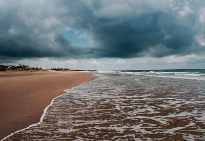 Scenic view of beach against cloudy sky