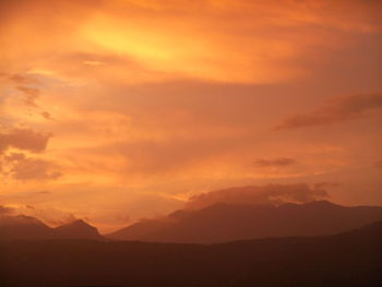 Scenic view of silhouette mountains against orange sky