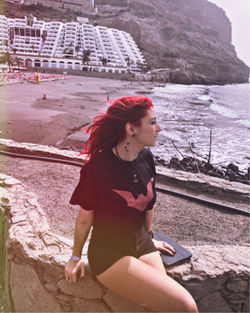 Young woman looking at camera while sitting on beach