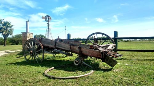 Abandoned cart on field against sky