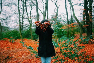 Woman holding leaves at forest during autumn 