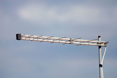 Low angle view of bird perching on pole against sky