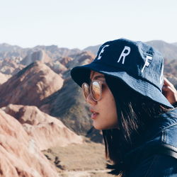 Side view of young woman standing against mountains