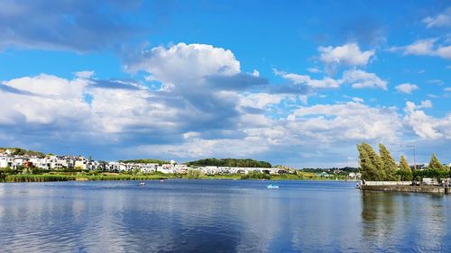 Scenic view of river by buildings against sky