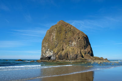 Rock formations on beach against blue sky