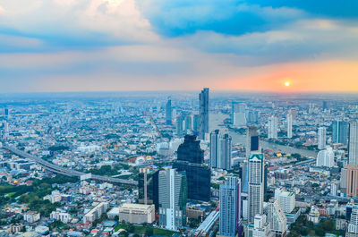 Aerial view of buildings in city against cloudy sky