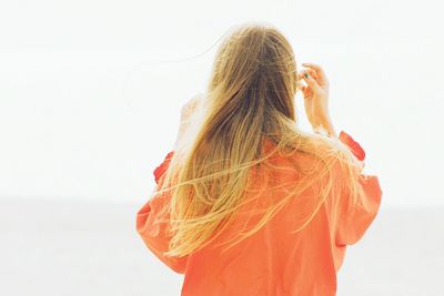 Rear view of woman standing on beach against clear sky