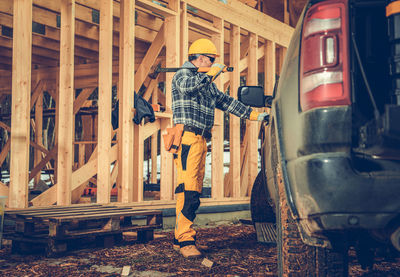 Full length of construction worker standing by truck