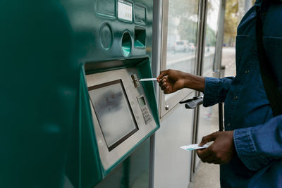 Businessman buying ticket while inserting credit card through machine