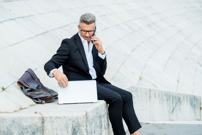 Businessman using mobile phone while sitting outdoors