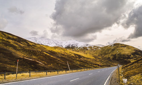 Country road against cloudy sky