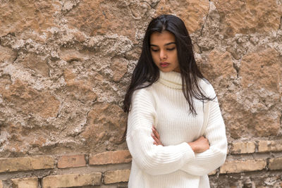 Beautiful young woman standing against wall