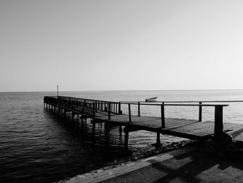 View of jetty in calm sea against clear sky