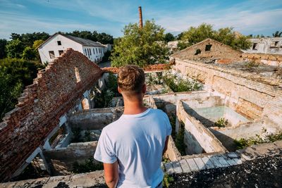 Rear view of man standing by abandoned house