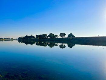 Scenic view of lake against clear blue sky