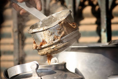 Close-up of container pouring tea in kettle