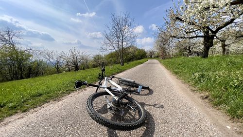 Low section of man riding bicycle on field against sky