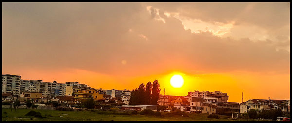 Buildings in town against sky during sunset