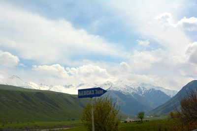 Road sign on landscape against sky