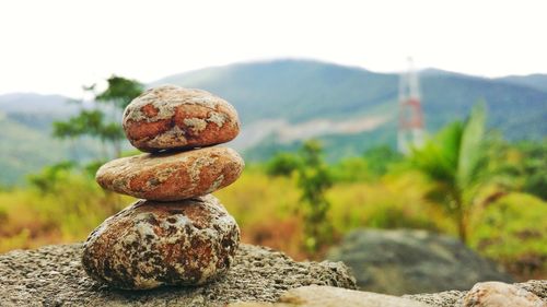 Close-up of stone stack on rock against sky