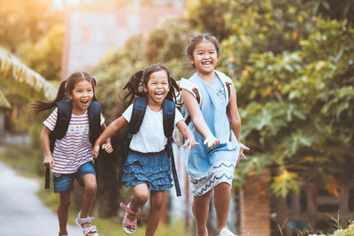 Happy backpack siblings running on road