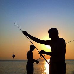 Silhouette of people fishing at sunset