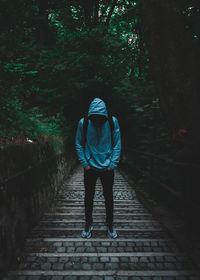 Rear view of man walking on footpath in forest