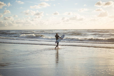 Silhouette woman standing on beach against sky