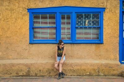 Full length portrait of smiling woman walking on window