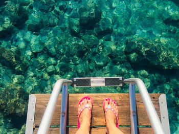 Low section of woman standing on pier by sea