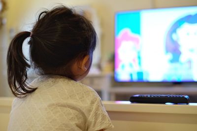 Rear view of girl watching tv