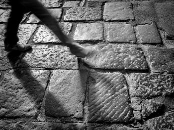 Low section of man walking on stone paving