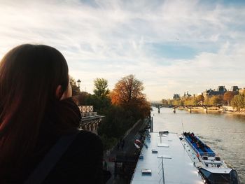 Rear view of woman on river in city against sky