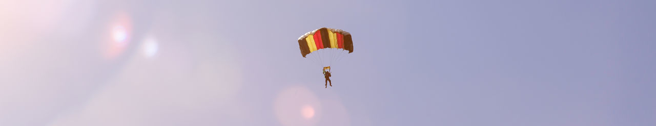 Low angle view of person paragliding against sky