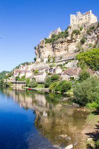 Buildings at waterfront against blue sky