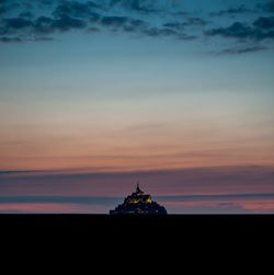 Silhouette of building against cloudy sky during sunset